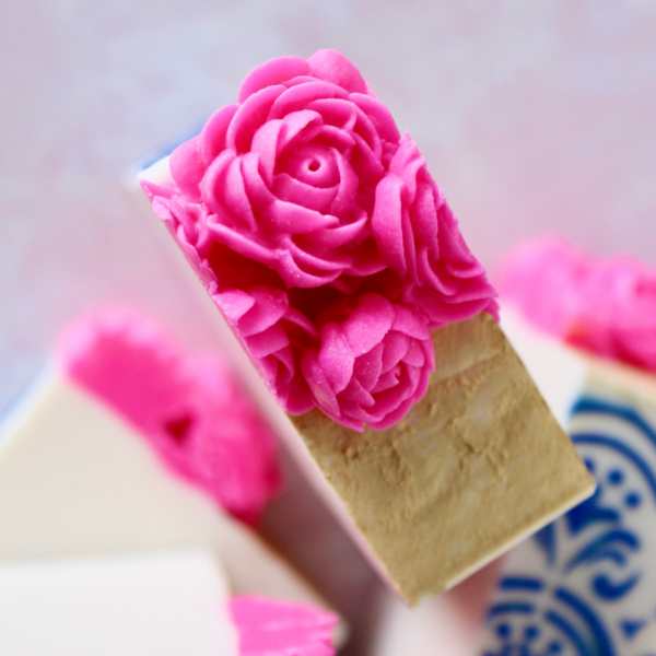 close up view of top of cut soap with magenta flowers and gold top