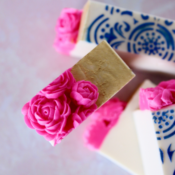 close up view of top of cut soap with magenta flowers and gold top and side