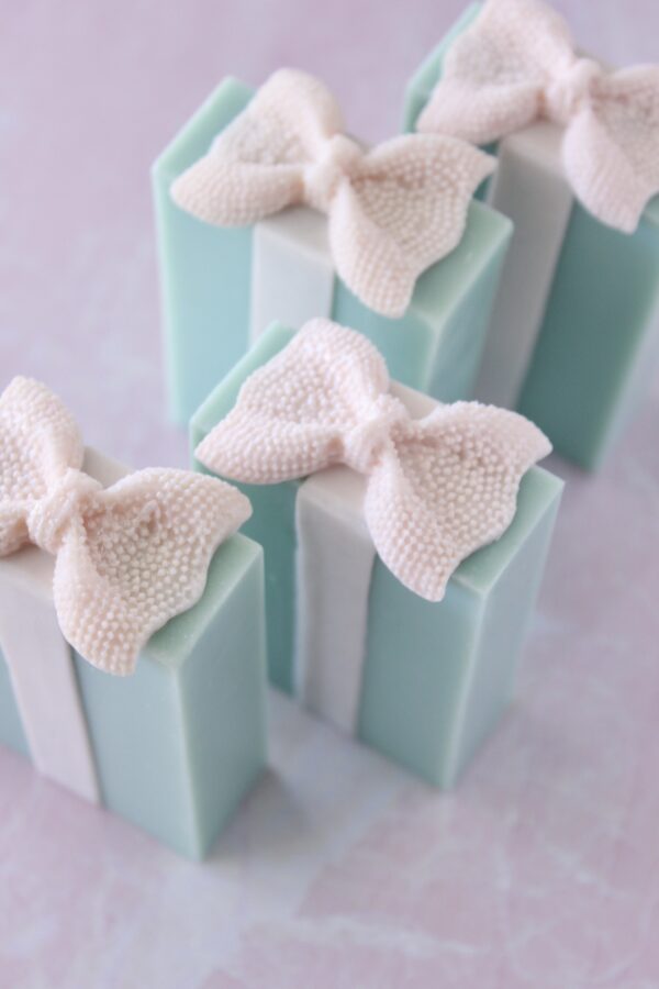 Top view of little blue bars pink textured bow on top of a turquoise blue bar