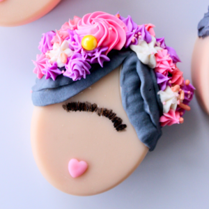 Close up view of Oval Frida Bar with pink lips, black etched unibrow, black piped hair, and pink, purple, and white flowers piped on hair