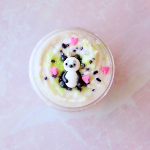 jar with panda sprinkle laying on a bed of colored sprinkles on whip sugar scrub.
