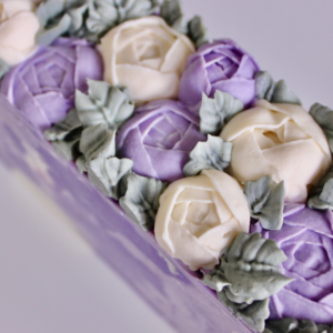 Purple and white piped soappeonies on top of a purple and white soap