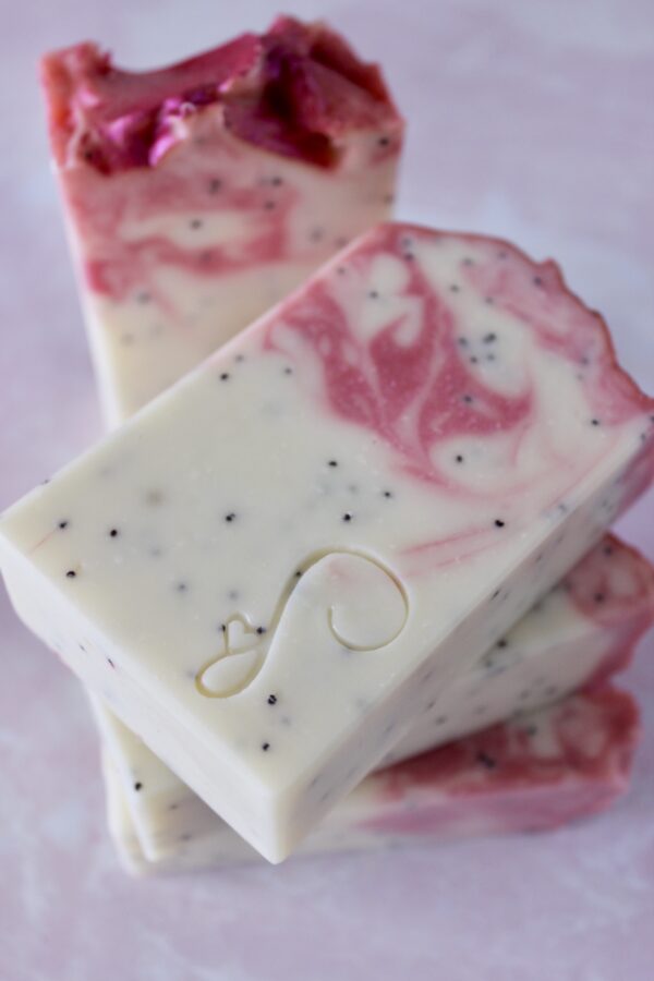 White dragonfruit soap bar with pink swirls and poppy seeds inside