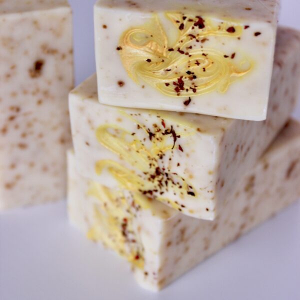 Three Citrus Sea Moss Butter Bars stacked on it's side showing yellow mica swirl and dried flowers on top
